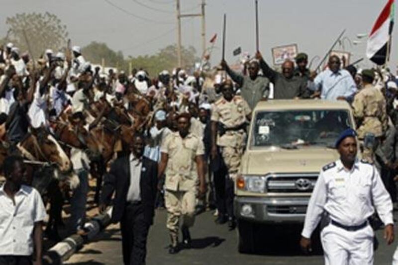Sudanese president Omar al Bashir, top second right, waves his cane in the air as supporters greet him in the North Darfur state capital of el-Fasher.
