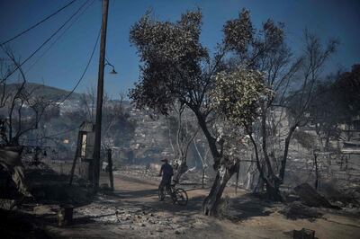 A picture taken on September 10, 2020 in Moria shows a migrants walking with his bike through the Moria refugee camp, two days after Greece's biggest and most notorious migrant camp, was destroyed by fire. Thousands of asylum seekers on the Greek island of Lesbos languished on roadsides on Thursday, homeless and hungry after the country's largest camp burned down, with local officials stonewalling government efforts to create new temporary shelters.
 / AFP / LOUISA GOULIAMAKI
