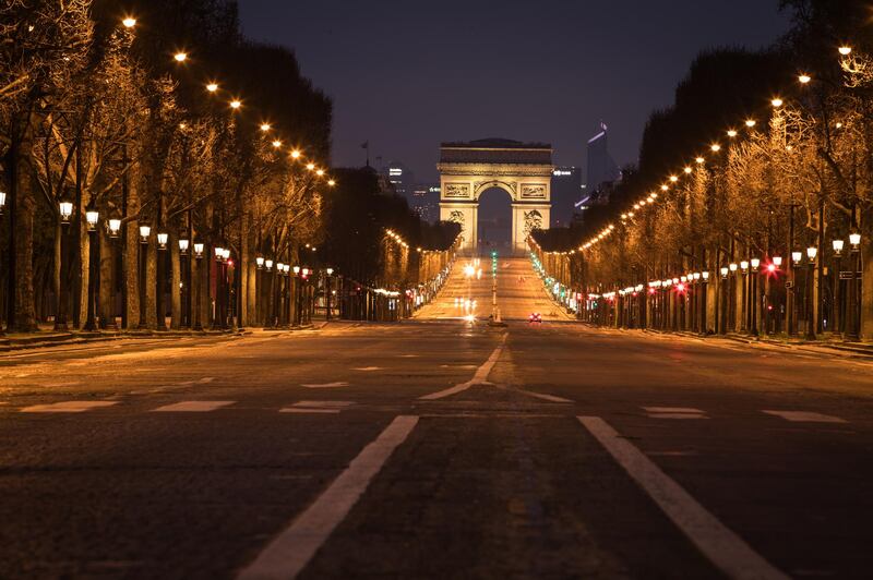 Street lights illuminate a deserted Champs Elysees leading to the Arc de Triumph monument  in central Paris on March 21, 2020, as a strict lockdown is in effect across France to stop the spread of COVID-19, caused by the novel coronavirus. - A strict lockdown requiring most people in France to remain at home came into effect at midday on March 17, 2020, prohibiting all but essential outings in a bid to curb the coronavirus spread. The government has said tens of thousands of police will be patrolling streets and issuing fines of 135 euros ($150) for people without a written declaration justifying their reasons for being out. (Photo by JOEL SAGET / AFP)