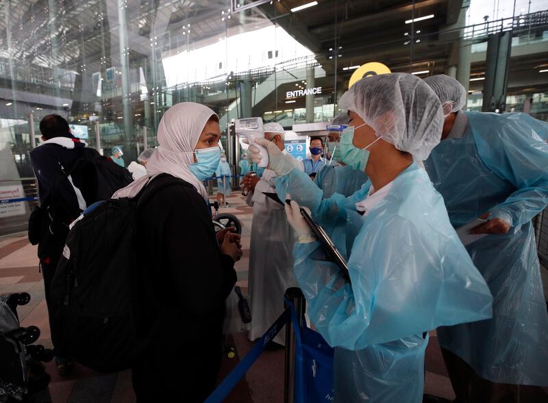 Thai health officials check the body temperature of an arriving foreigner prior to heading to a 14-day quarantine period, at the Suvarnabhumi International Airport. EPA