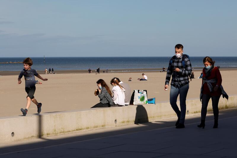 People wearing protective face masks walk near the beach in Dunkirk. Reuters