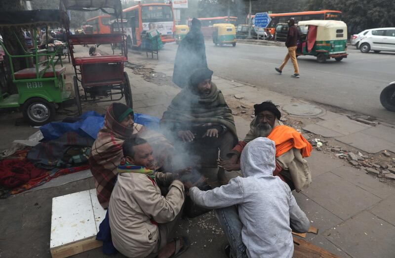 epa08095601 People sit next to a fire on a cold morning in New Delhi, India, 31 December 2019. Northern India remains in the grip of cold as minimum temperature in the national capital New Delhi dropped below the three degrees Celsius mark.  EPA/RAJAT GUPTA