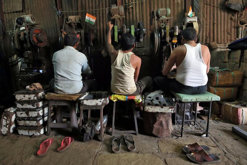 Workers operate metal cutting machines inside a workshop in Mumbai. Reuters