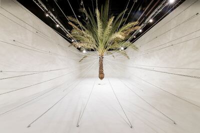 Christopher Joshua Benton's 'The World Was My Garden' is anchored by the striking sculpture of an enchained palm tree, suspended in the air. Photo: Abu Dhabi Art