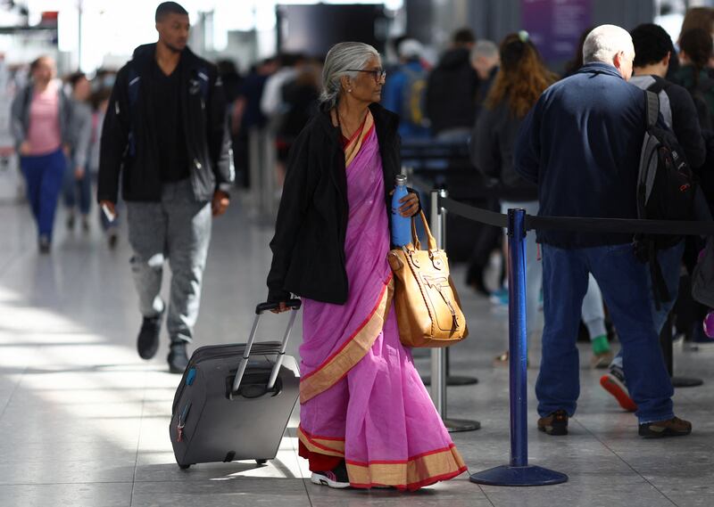 A woman walks with her luggage as passengers queue to enter airport security, at Terminal 5 of Heathrow Airport, in London, Britain. London is one of the destinations that has seen a steep rise in the cost of flights to. Reuters
