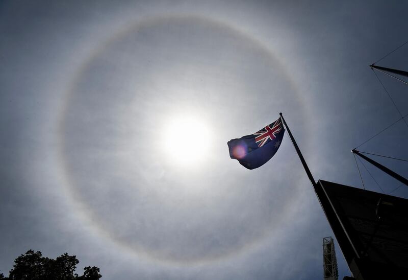 The Australian flag is seen in a halo around the sun, an optical phenomena produced by light interacting with ice crystals suspended in the atmosphere, in Melbourne on December 30, 2020. / AFP / William WEST
