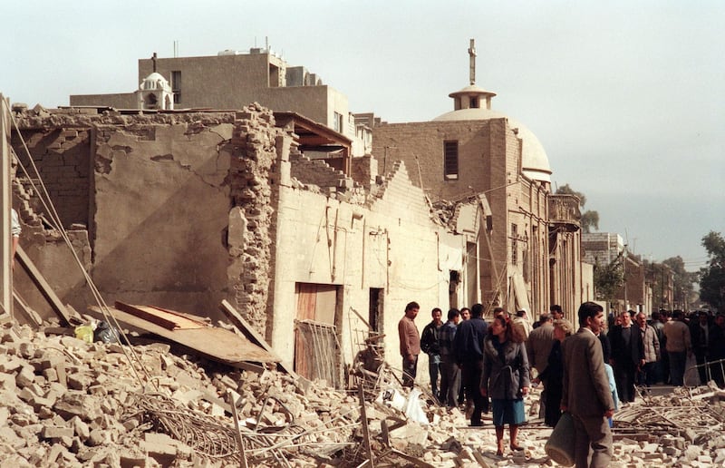 Iraqi civil defence workers and civilians shown in a photo dated 16 February 1991 looking at the damage near a Christian church caused by an allied bombing raid in a Baghdad street. (Photo by STR / AFP FILES / AFP)