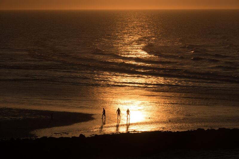 People walk on the Gold Beach at Ouistreham viewed from the deck of a cross-channel ferry.