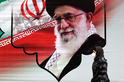 An Iranian woman walks past a mural showing Iran's supreme leader Ayatollah Ali Khamenei in the capital Tehran on March 9, 2022. AFP