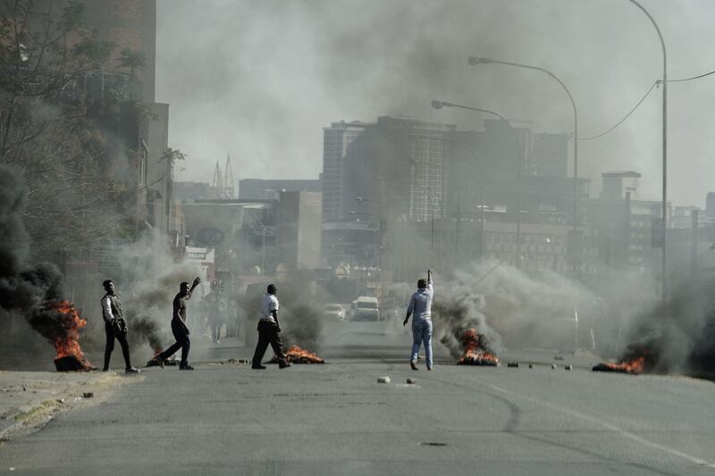 Protesters burn tires in Jeppestown. The corruption inquiry is examining allegations that Mr Zuma allowed three Indian-born businessmen, Atul, Ajay and Rajesh Gupta, to plunder state resources and peddle influence over government policy.