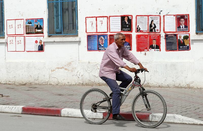 A Tunisian man rides a bicycle past posters of Tunisian presidential candidates on the first day of presidential campaign in Tunis, Tunisia.  EPA