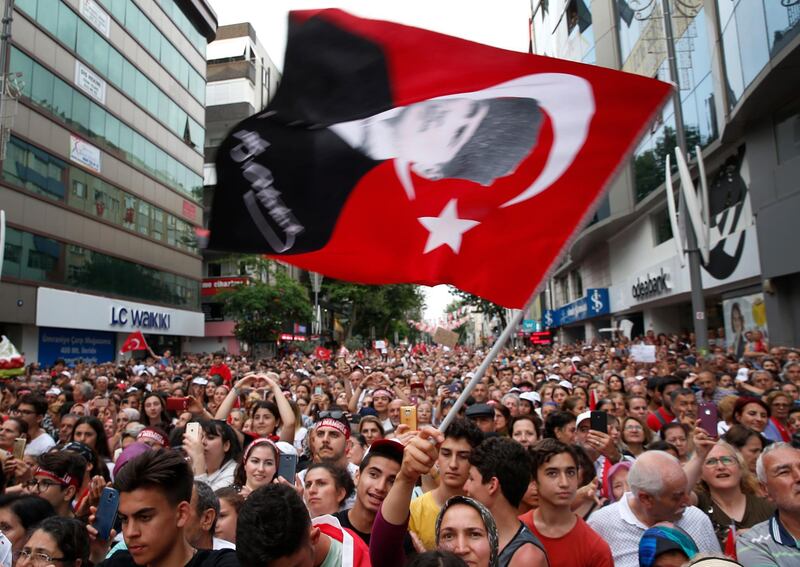 A supporter of Ekrem Imamoglu, candidate of the secular opposition Republican People's Party, or CHP, waves a Turkish flag with a picture of modern Turkey's founder Mustafa Kemal Ataturk, during a rally in Istanbul, Wednesday, June 19, 2019, ahead of June 23 re-run of Istanbul elections. The 49-year-old candidate won the March 31 local elections with a slim majority, but after weeks of recounting requested by the ruling party, Turkey's electoral authority annulled the result of the vote, revoked his mandate and ordered the new election. (AP Photo/Lefteris Pitarakis)