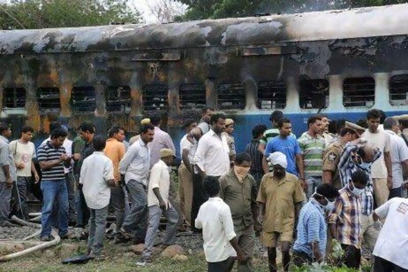 Railway workers and officials inspect the burnt coach of a passenger train at Nellor.