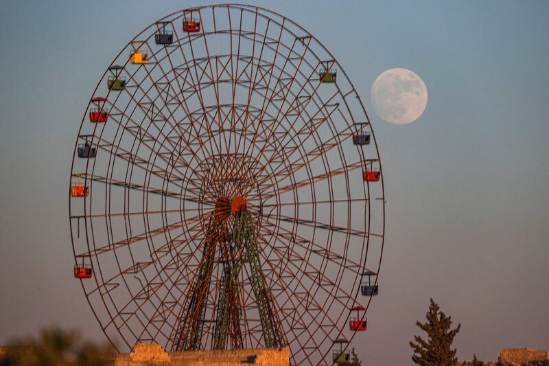 The waxing gibbous moon rises behind a rundown Ferris wheel at an abandoned amusement park near Al-Nayrab, a village ravaged by bombardments by pro-government forces in Idlib province, Syria. AFP
