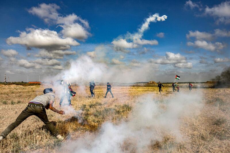 Protesters throw back tear gas grenades fired by Israel during a demonstration at the Gaza border. AFP