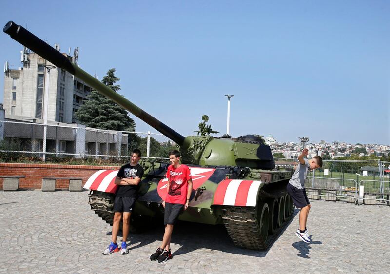 People pose for a photograph in front of a former Yugoslav army T-55 battle tank in front of the northern stand of the Rajko Mitic stadium in Belgrade. EPA