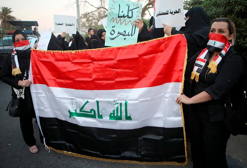 Women hold a national flag and banners with Arabic that reads, "we are all Basra,  freedom for detainees and save Basra," during a demonstration in the southern city of Basra, Iraq, Tuesday, Sept. 25, 2018. The protest comes hours after masked gunmen shot dead Soad al-Ali, a human rights activist and mother of four, who has been involved in organizing protests demanding better services in Basra. (AP Photo/Nabil al-Jurani)