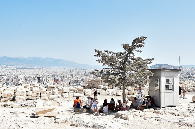 Tourists shelter from the sun atop the Acropolis in Athens. Getty Images