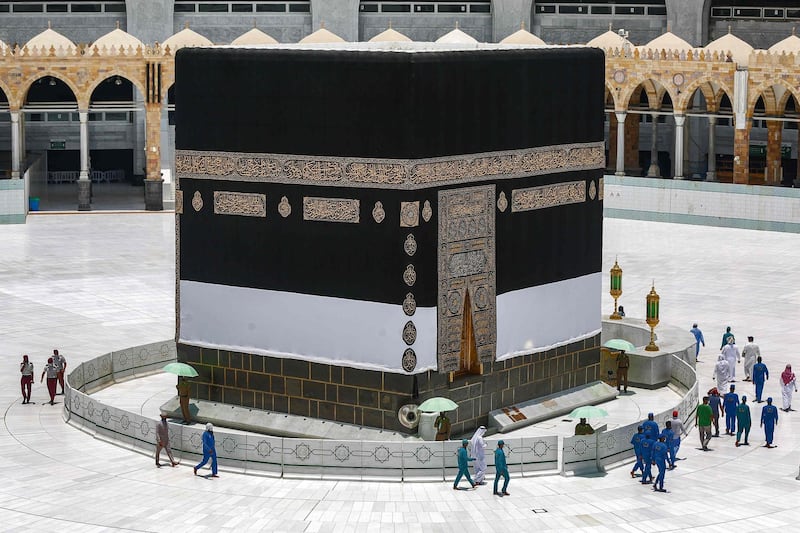 Workers at the the Grand Mosque complex in Saudi Arabia's holy city of Mecca, mask-clad due to the COVID-19 coronavirus pandemic, walk around the the Kaaba, Islam's holiest shrine, at centre of the complex ahead of the annual Hajj pilgrimage season.  AFP