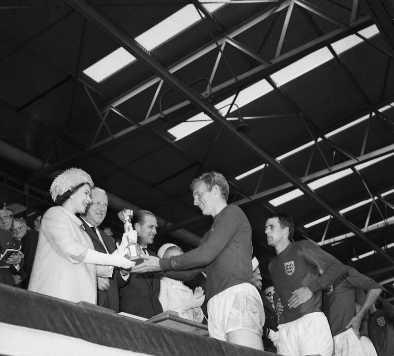 Queen Elizabeth II of Great Britain presenting the Jules Rimet trophy to the England captain, Bobby Moore, after the teams World Cup final victory over West Germany. Geoff Hurst, who scored a hat-trick in the game stands behind Moore, and Prince Philip, Duke of Edinburgh, looks on. (Photo by Evening Standard/Hulton Archive/Getty Images)