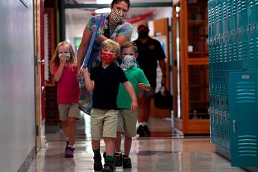 Teacher Holly Rupprecht carries Plexiglass panels to her classroom with help from Maelene Wright, left, her brother Hank Wright, and Rupprecht's son Theo at Zion Lutheran School in Bethalto, Illinois, US, on Monday, July 20, 2020. The teacher designed her own table dividers with construction help from her father. AP