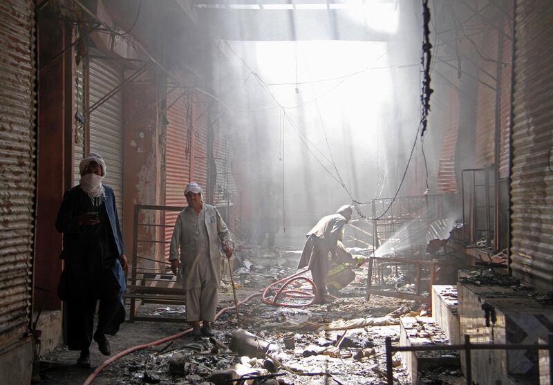 An Afghan firefighter sprays water on a burning shop after a Taliban attack in Ghazni. Reuters