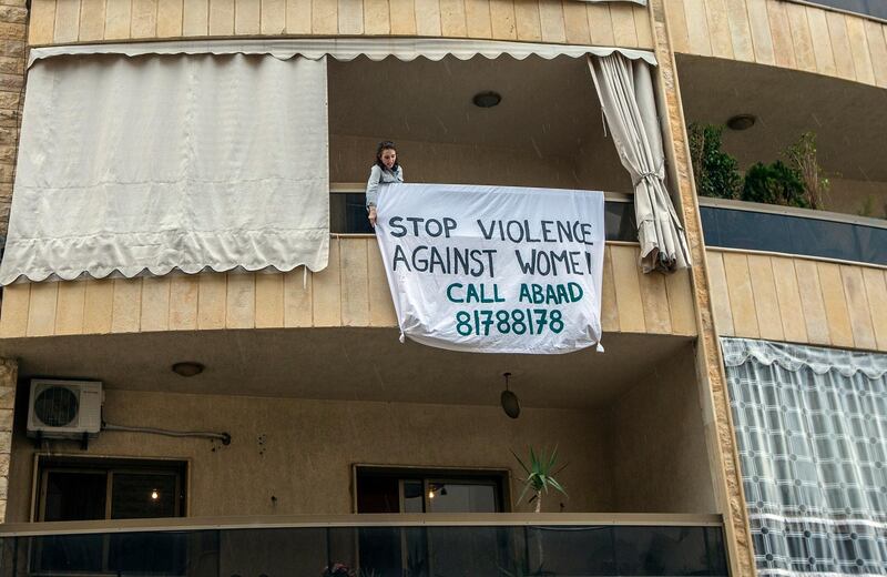 epa08366817 A woman hangs a sign on her balcony with phrases protesting domestic violence against women in Beirut, Lebanon, on April 16, 2020. The protest is organizing by ABAAD, a non-profit, non-politically affiliated, non-religious civil association that aims to achieve gender equality as an essential condition to sustainable social and economic development in the MENA region. EPA