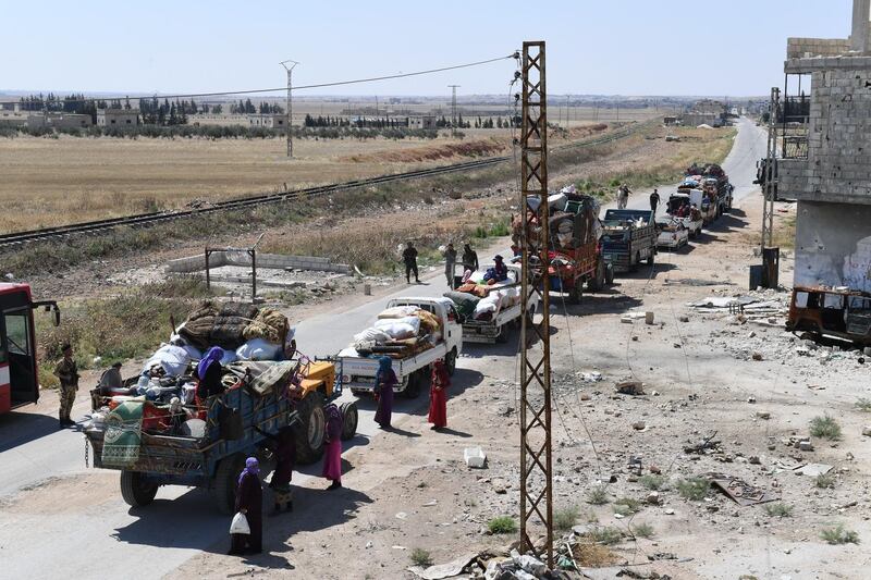 Syrian soldiers stand guard by a convoy returning displaced people home into government-controlled territory at Abu al-Zuhur checkpoint in the western countryside of Idlib province, on June 23, 2018,.  / AFP / George OURFALIAN
