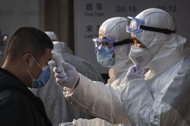 A Chinese health worker checks the temperature of a person entering a subway station in Beijing, China. Getty Images