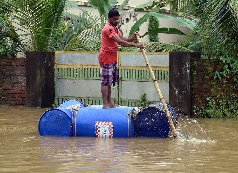 An Indian man paddles down a street on a makeshift raft.  EPA