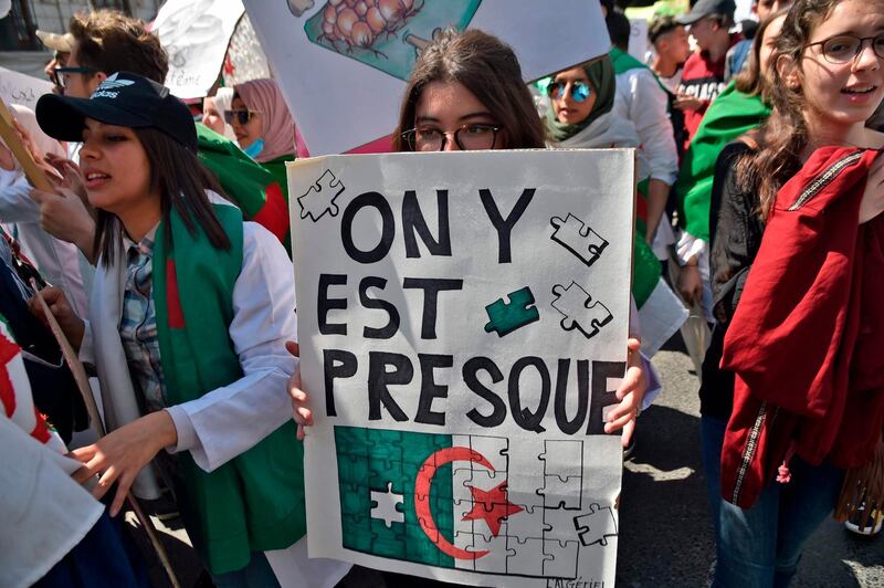TOPSHOT - Algerian students hold placards on April 30, 2019 as they continue their weekly protests in the capital Algiers to demand the overthrow of the "system" and trials for members of the ousted president's inner circle. The placard reads in French "We are almost there". Former Algerian prime minister Ahmed Ouyahia was questioned the same day in a widening investigation into alleged corruption in the inner circle of ousted president Abdelaziz Bouteflika, state television reported. / AFP / RYAD KRAMDI                        

