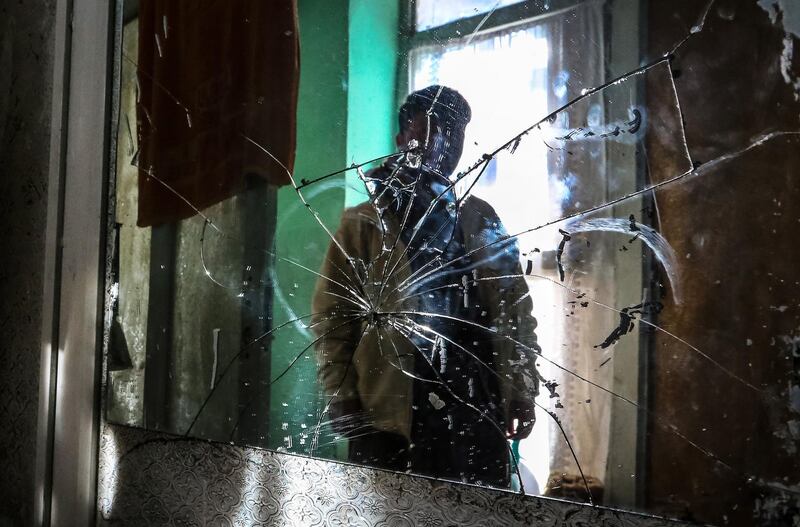 An Afghan boy look at the broken glass at the site of a rocket attack at a residential house in Kabul on December 12. EPA