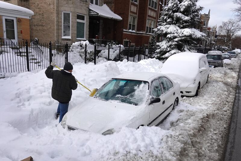A resident clears snow from his car in the Humboldt Park neighborhood on February 1, 2021 in Chicago, Illinois. More than a foot of snow fell in some areas of the city during a winter storm that lasted most of the past weekend.  AFP