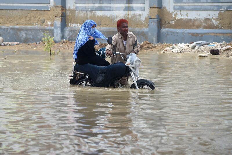 Commuters wade through a flooded street. AFP