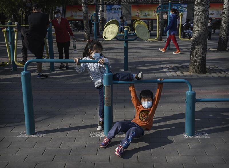 A Chinese boy and girl wear protective masks as they play on exercise equipment at Ritan Park in Beijing. Getty Images