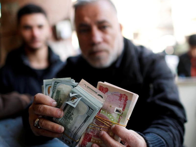 A man holds money as he poses for a picture at a foreign currency exchange market in Baghdad, Iraq, December 20, 2020. REUTERS/Thaier Al-Sudani