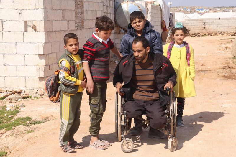 Syrian Ibrahim al-Ali is assisted by his children, at the Deir Hassan camp for the displaced where they reside, in Idlib's northern countryside near the Turkish border. The 33-year-old father of four first lost three fingers, later his hearing in one ear. Then all at once, both legs and eyes. Ibrahim al-Ali was wounded every time he tried to escape Syria's war.  AFP