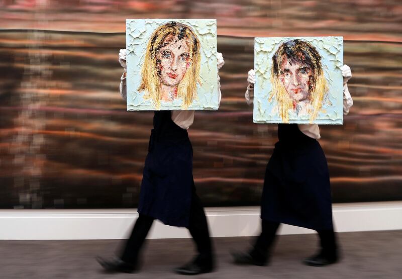 Two Sotheby's employees walk with Kaari Upson's oil on panel pictures 'For a Good Time' with the estimate value of £15,000-20,000 at the Sotheby's auction house in London. Over 300 works from Mario Testino's Remarkable Personal Art Collection are on display for the first time at Sotheby's in London. Frank Augstein / AP Photo