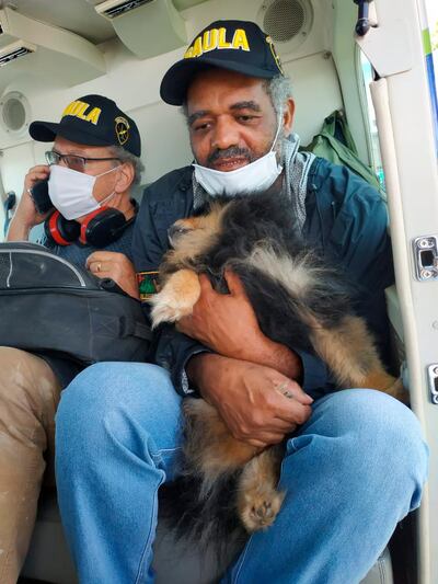 In this photo released by Colombia's Army Press Office, Daniel Max Guggenhein from Switzerland, left, and Jose Ivan Alburneque Matias from Brazil, right, sit in a helicopter after being rescued by Colombia's Army in Popayan, Colombia, Thursday, June 18, 2020. Both foreigners were kidnapped 3 months ago by dissents members of the Revolutionary Armed Forces of Colombia. Matias is holding his pet dog that was kidnapped along with his owner and accompanied him through the whole ordeal. (AP Photo/Colombia's Army Press Office)