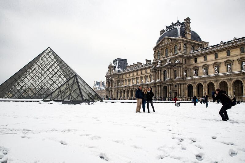 epa06502528 Tourists take pictures in the snow in front of the Louvre Pyramids in Paris, France, 07 February 2018. Temperatures dropped with snow flurries around the capital.  EPA/ETIENNE LAURENT