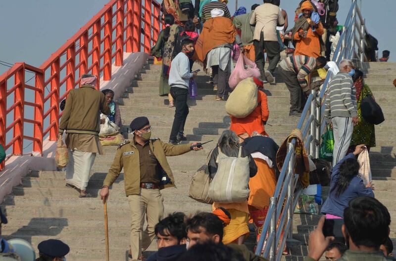 A police offer asks pilgrims to leave the banks of the river Ganges in Haridwar, India, as a precautionary measure after flash flooding in a tributary in Uttarakhand. AP