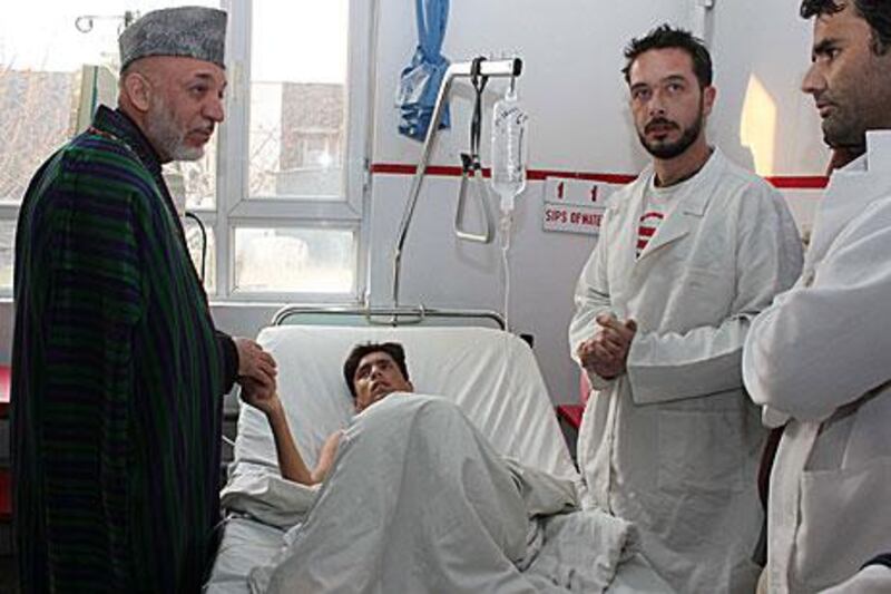 Hamid Karzai, the Afghan president, visits an injured man in a Kabul hospital the day after three bomb blasts killed at least 59 people in the country.
