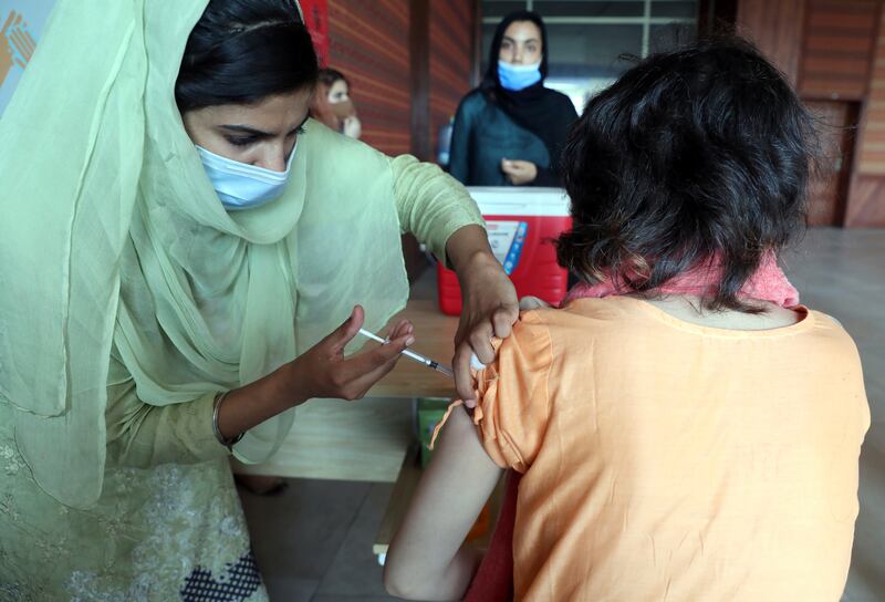A woman receives Pfizer-BioNTech's Covid-19 vaccine at a centre in Islamabad, Pakistan. The IMF said the investment to speed up the vaccination drive will boost the global economic activity by trillions of dollars over the next few years. AP
