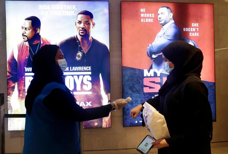 A Saudi movie viewer has her temperature taken at VOX Cinema hall in Jeddah, Saudi Arabia after the announcement of easing of lockdown measures. AP Photo