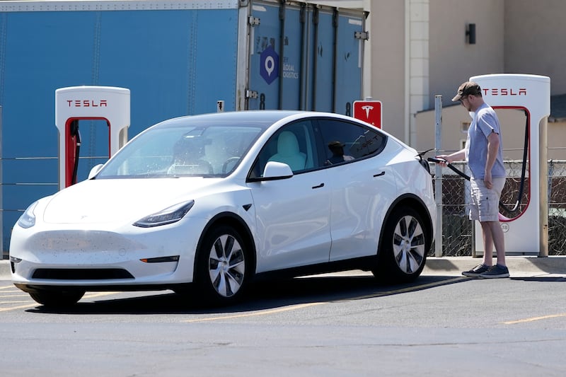 A Tesla owner charges his vehicle at a charging station. AP Photo