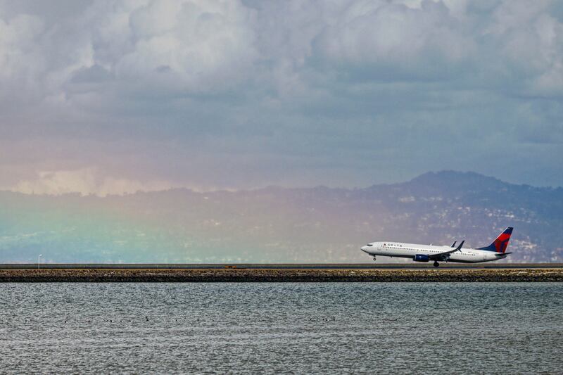 A plane lands on a runway at San Francisco International Airport at the base of a rainbow, in California.  AP