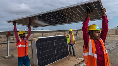 Workers carry a solar panel for installation in the western Indian state of Gujarat last September. AP