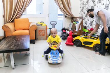 Toddler Aarev Shetty, 2, rides his toy car at home with his father, Sushant. Reem Mohammed / The National