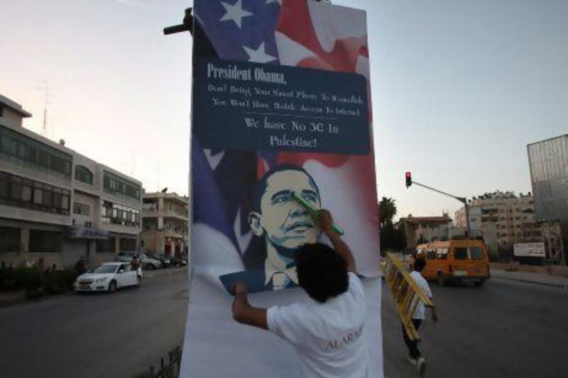 A Palestinian activist sticks a poster with a slogan against the upcoming visit of US president Barack Obama to the West Bank city of Ramallah.