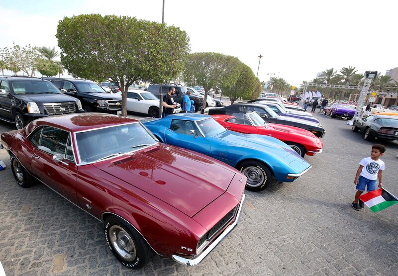 A Camaro leads a line of classic cars.
